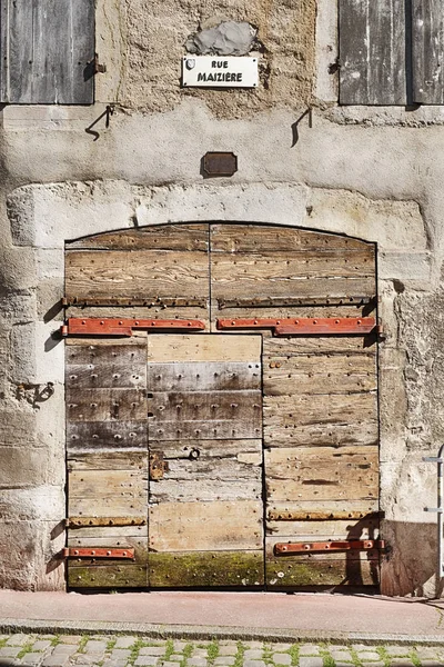 An old garage door made of many pieces of wood has endured centuries of weather on Rue Maziere in the town of Beaune in the Burgundy region of France.