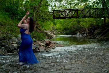 Ormanda şelalenin yanında poz veren güzel bir kadın.