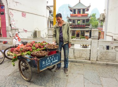 Yangshuo, Çin - 20 Ekim 2013: Satıcı onun arabası Yangshuo, Çin ile sokakta meyve satıyor. Guilin Guangxi yakınındaki bir popüler turistik ilçe ve Yangshuo şehridir.