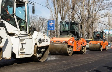 Kiev, Ukrayna 29 Mart 2017: Yol inşaatı parke üzerinde yol silindirleri taze asfalt yolun Rusanovka bölgesinde tüm genişliği üzerinden sıkıştırma çalışır. Kiev, Ukrayna. İnsanlar ve inşaat iş kavramı