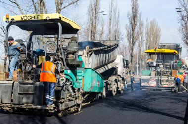 Kiev, Ukrayna 29 Mart 2017: Yol inşaatı parke üzerinde yol silindirleri taze asfalt yolun Rusanovka bölgesinde tüm genişliği üzerinden sıkıştırma çalışır. Kiev, Ukrayna. İnsanlar ve inşaat iş kavramı