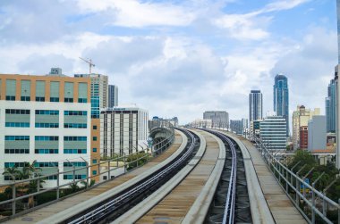 Modern binalar ve gökdelenler arasında yükseklikte geçen Metromover raylar. Metromover treni Financial Center, Miami, Southern Florida, USA'daki istasyona gidiyor. Metromover ücretsiz toplu taşıma (monorail), Miami, Güney Florida, Abd. Cityscape.