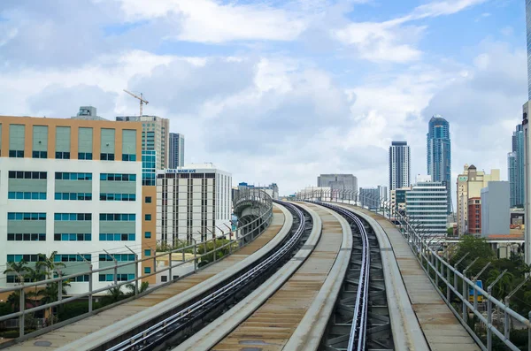 Modern binalar ve gökdelenler arasında yükseklikte geçen Metromover raylar. Metromover treni Financial Center, Miami, Southern Florida, USA'daki istasyona gidiyor. Metromover ücretsiz toplu taşıma (monorail), Miami, Güney Florida, Abd. Cityscape.