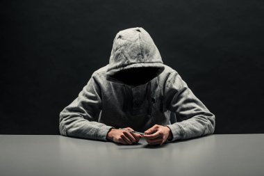 Kafasına gri kapüşonlu Addict koyu siyah bir arka plan üzerinde bağımlılığı muzdarip.