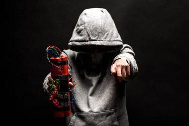 The silhouette of a man in the hood on a black background, his face is not visible, shows hands gesture and a time bomb. The concept of criminal terrorism clipart