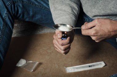 Bir uyuşturucu bağımlısı bir kaşık kokain erime elleri. Bir adam bir kaşık çakmak üzerinde tutar. Uyuşturucu ve suç kavramı.