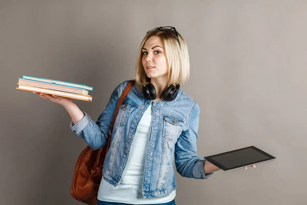 Kitap e-kitap vs. Geleneksel bir ders kitabı tutarak ve e-kitap üzerinde gri arka plan izole okuma kız öğrenci. Kağıt kitap ve e-öğrenme araçları arasında seçim. Modern eğitim kavramı.