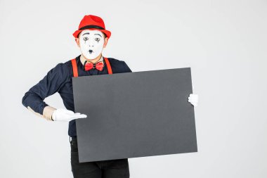 Mutlu MIME sanatçısı beyaz arka planda beyaz bir tahta tutuyor..