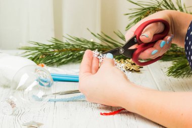 Noel süsleri, toplar, oyuncak ve hediye kutuları eski bir ahşap panosuna. Eller Noel süsleri yapmak.