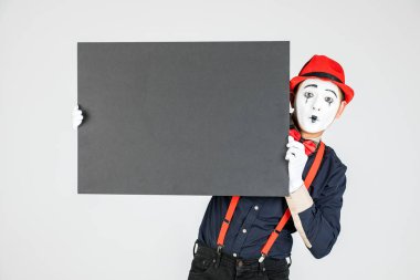 Mutlu MIME sanatçısı beyaz arka planda beyaz bir tahta tutuyor..