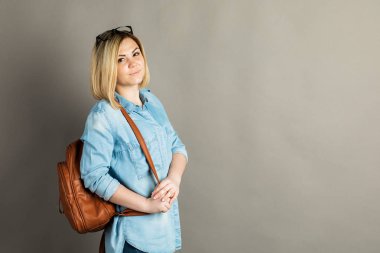 Gri bir arka plan üzerinde bir sırt çantası ile bir kız portresi