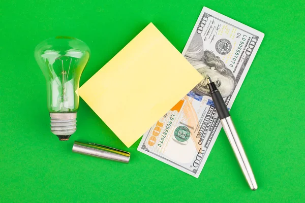 Lightbulb, electricity bills. Energy saving concept. On a green background.