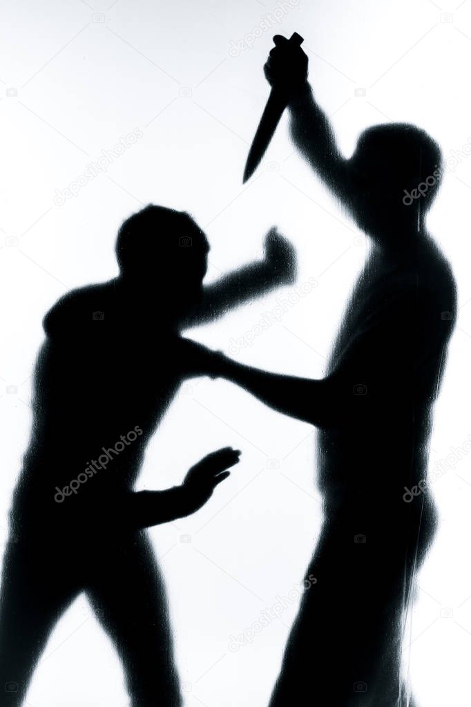 Self-defense battle silhouette. A man fights against an aggressor with a knife. Fight for life against terrorists.