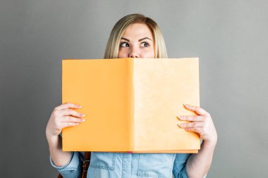 Gri bir arka plan üzerinde izole kitap okumak güzel akıllı kız