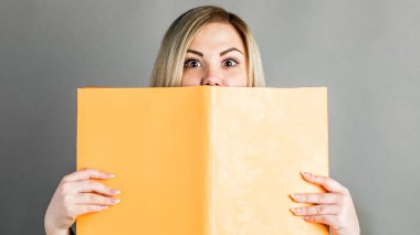 Gri bir arka plan üzerinde izole kitap okumak güzel akıllı kız