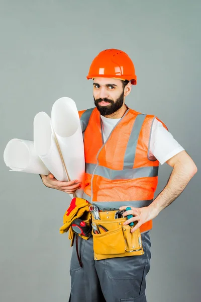Builder or worker in a protective helmet with drawings in his hands. Isolated on grey background.