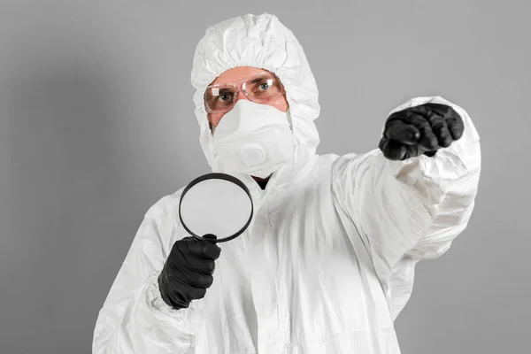 Scientist Protective Clothing Glasses Respirator Looks Magnifying Glass Gray Background — Stock Photo, Image