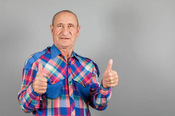 Happy satisfied older older man showing thumb up on grey background