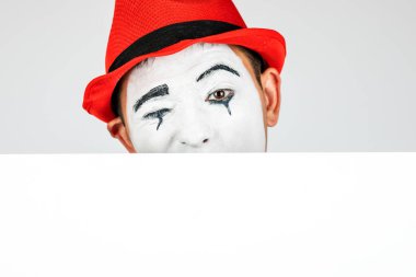 Mutlu MIME sanatçısı beyaz arka planda beyaz bir tahta tutuyor.