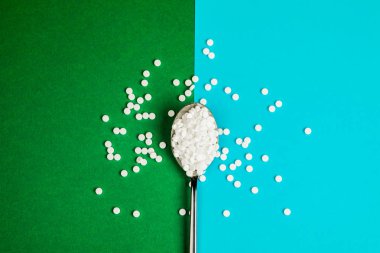 Yeşil ve mavi arka plan üzerinde bir kaşık ile şeker değiştirme tabletleri.