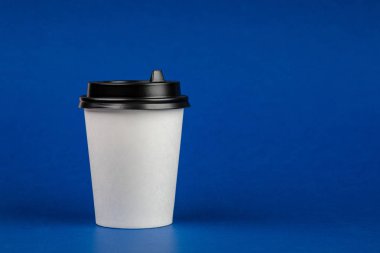 Kağıt kahve kap mavi arka plan üzerinde siyah kapaklı. Take-away içecek kapsayıcı. İçki Kupası şablonu tasarımınız için
