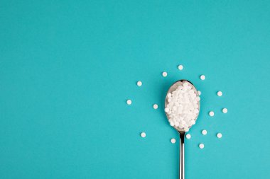 Şeker yerine hap mavi bir arka plan üzerine bir kaşık.