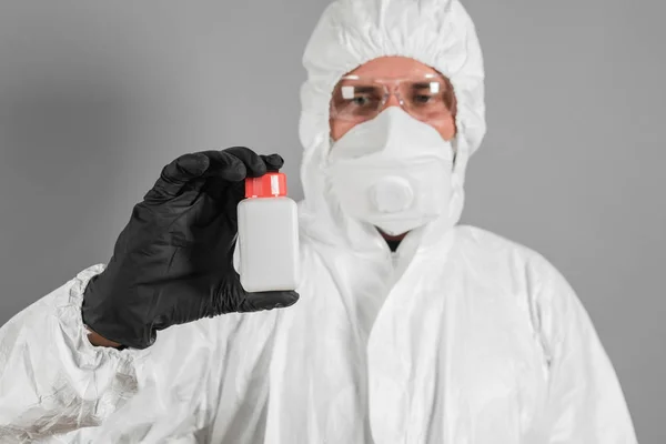 A medical scientist or a policeman wearing protective clothing holds a plastic tube in his hand. The concept of health and crime.
