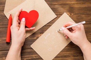 Üstten Görünüm. Kızın Saint Sevgililer günü aşk mektubu yazma el. El yapımı kart kırmızı kalp şeklinde rakam ile. 14 Şubat tatil kutlaması. Sevgililer günü kavramı kopya alanı ile.