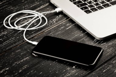 Usb kablosu telefonunuzu ve dizüstü bilgisayarınızı bağlar. Siyah masanın üzerinde