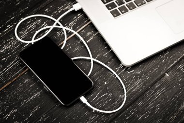 Usb kablosu telefonunuzu ve dizüstü bilgisayarınızı bağlar. Siyah masanın üzerinde