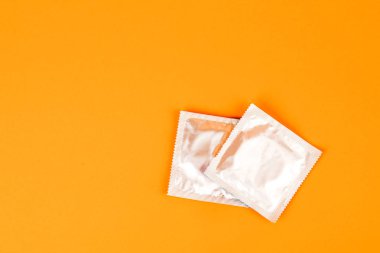 Turuncu arka planda prezervatifler. Önleme ve güvenli seks kavramı
