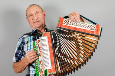 Bir adamın portresi, büyükbaba akordeon oynar. Gri arka planda.