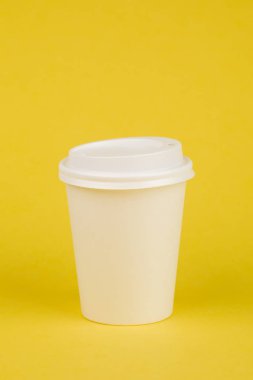 Sarı arka plan üzerinde beyaz kapaklı kağıt kahve kabı. Al