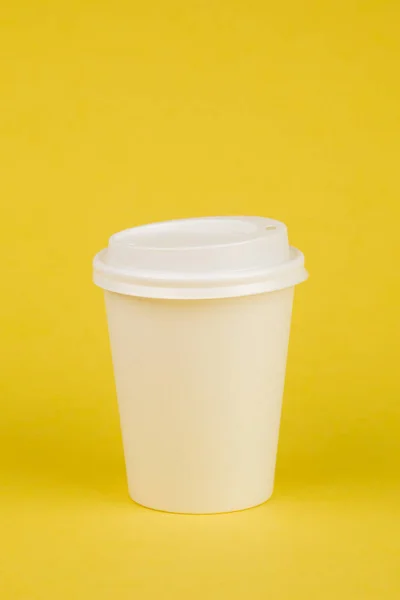Papier-Kaffeebehälter mit weißem Deckel auf gelbem Hintergrund. nehmen — Stockfoto