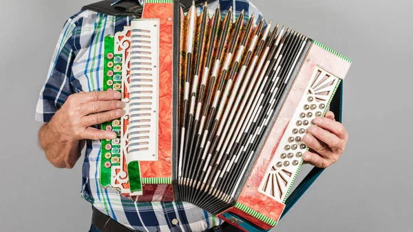 Porträt eines Mannes, Großvater spielt Ziehharmonika. auf einem grauen Ba — Stockfoto