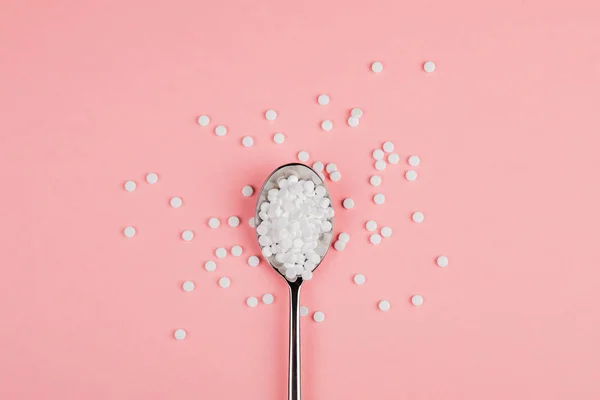 Замена сахара таблетки ложкой на розовом фоне — стоковое фото