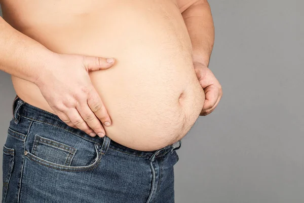 Tlustý Muž, kontrola jeho váhy, na šedém pozadí — Stock fotografie