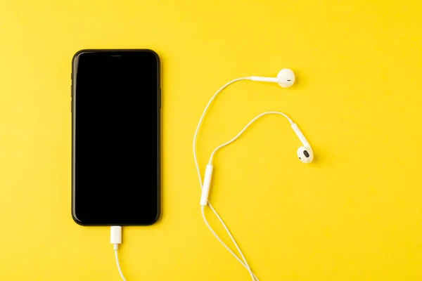 Smartphone se sluchátky na žlutém pozadí. Pohled z t — Stock fotografie