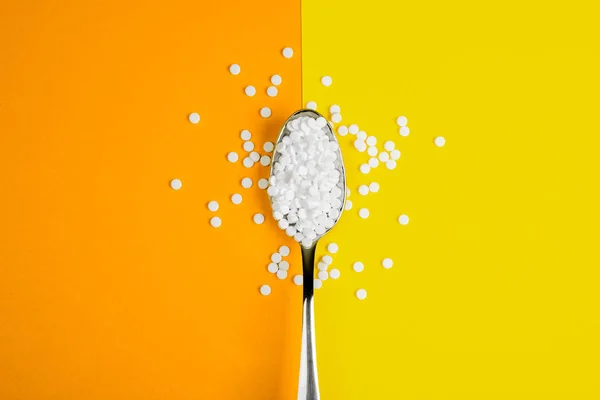 Pílulas de reposição de açúcar com uma colher em laranja e amarelo backgr — Fotografia de Stock