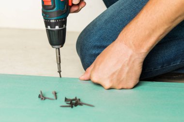 Builder spins the screw into a sheet of drywall. Construction an