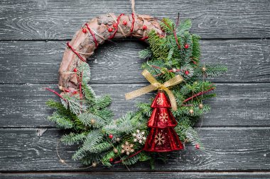 Siyah ahşap arka planda süsleri olan Noel çelengi.