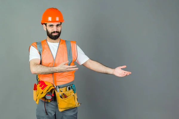 Homem Construtor com barba em pé sobre fundo cinza, espaço de cópia . — Fotografia de Stock