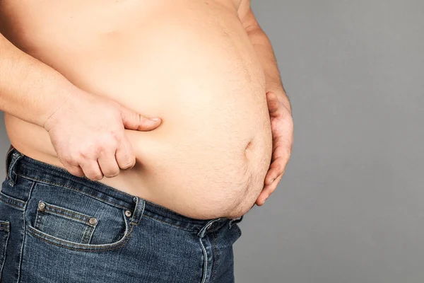 Dicker Mann, sein Gewicht prüfend, auf grauem Hintergrund — Stockfoto