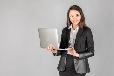 Gri bir wa üzerinde duran genç neşeli bir iş kadını fotoğrafı