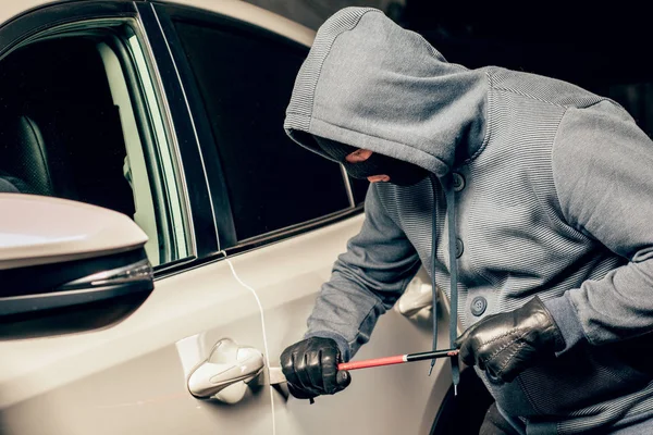 Zloděj mužů otevře dveře auta s páčem. — Stock fotografie