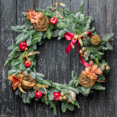 Siyah ahşap arka planda süsleri olan Noel çelengi.