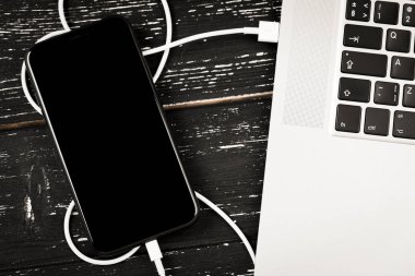 Usb kablosu telefonunuzu ve dizüstü bilgisayarınızı bağlar. Siyah masanın üzerinde.