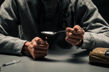 Çakmakla uyuşturucu hazırlayan bir adamın yakın çekim. Kavramı