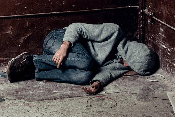 homeless guy sleeps on the floor in the slums
