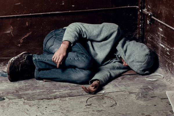 Бездомный спит на полу в трущобах.
